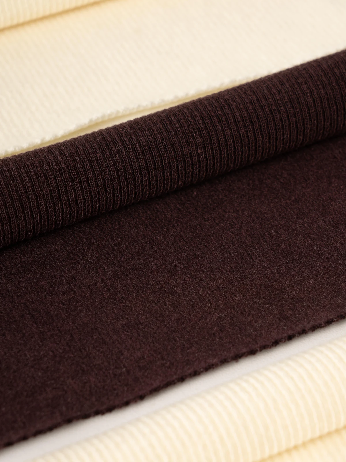 Ivory and burgundy ribbed fabrics arranged for sample comparison.