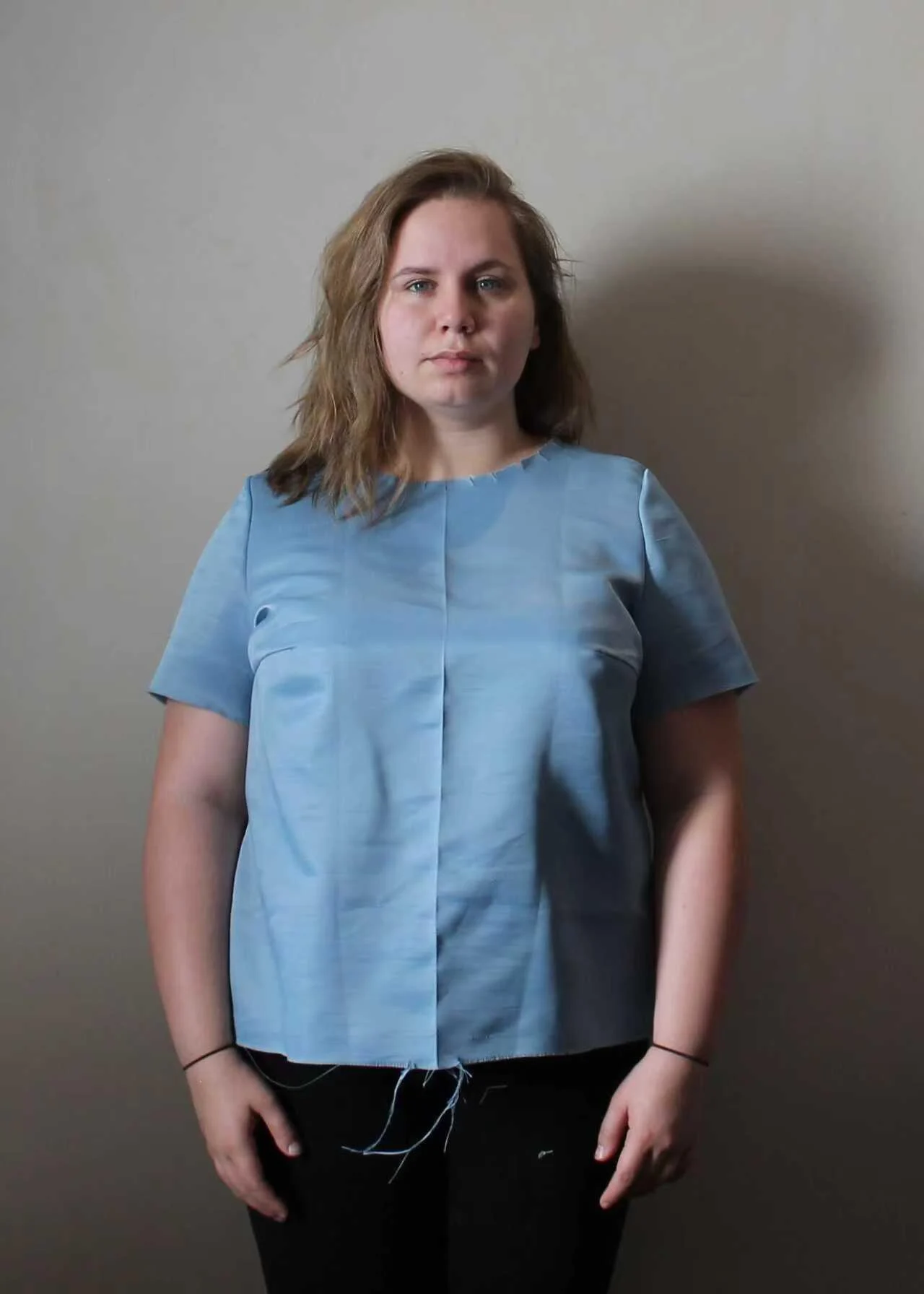 Front view of a woman wearing a blue development sample with visible fitting seams.