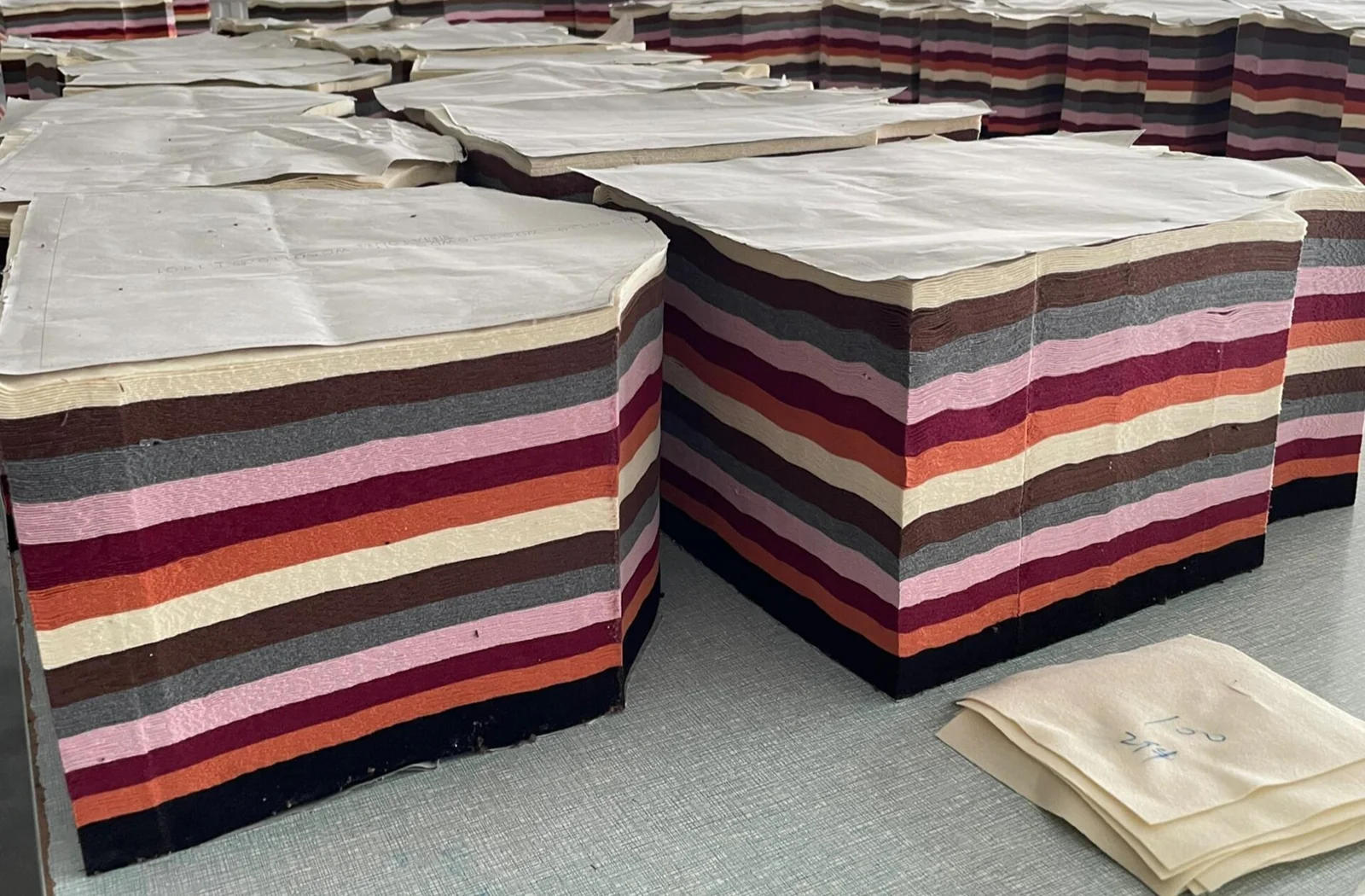Stacks of cut fabric components arranged on production tables.