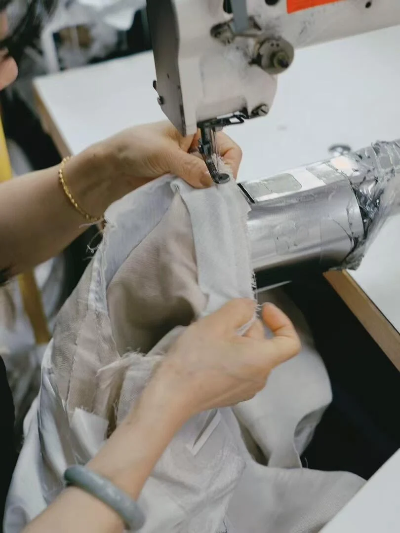 Hands guiding sample fabric through a sewing machine.
