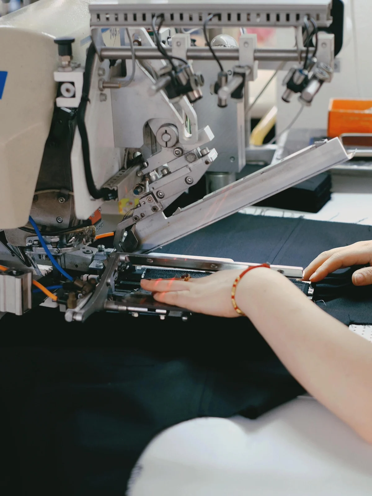 Fabric passing beneath an industrial sewing head.