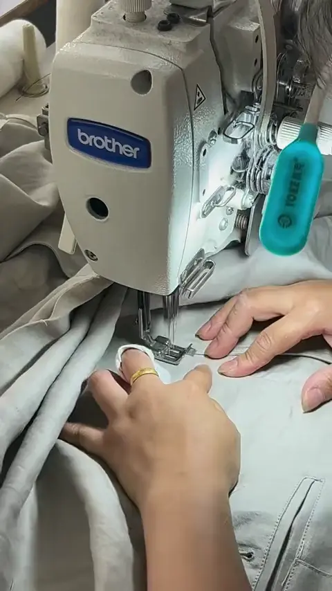 Hands guiding fabric through a sewing machine.