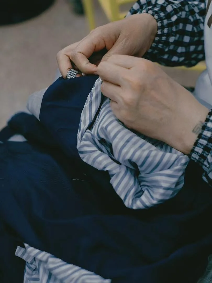 Hands reviewing the fabric and seam of a garment.