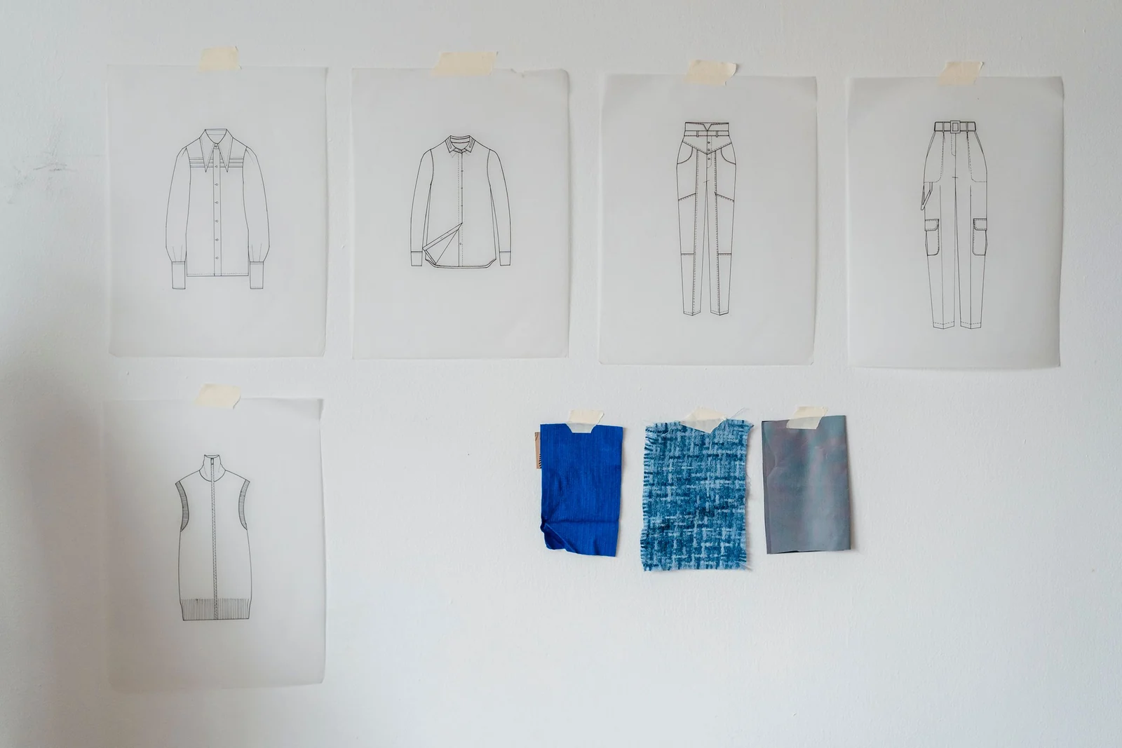 Garment sketches and material references pinned to a design wall.