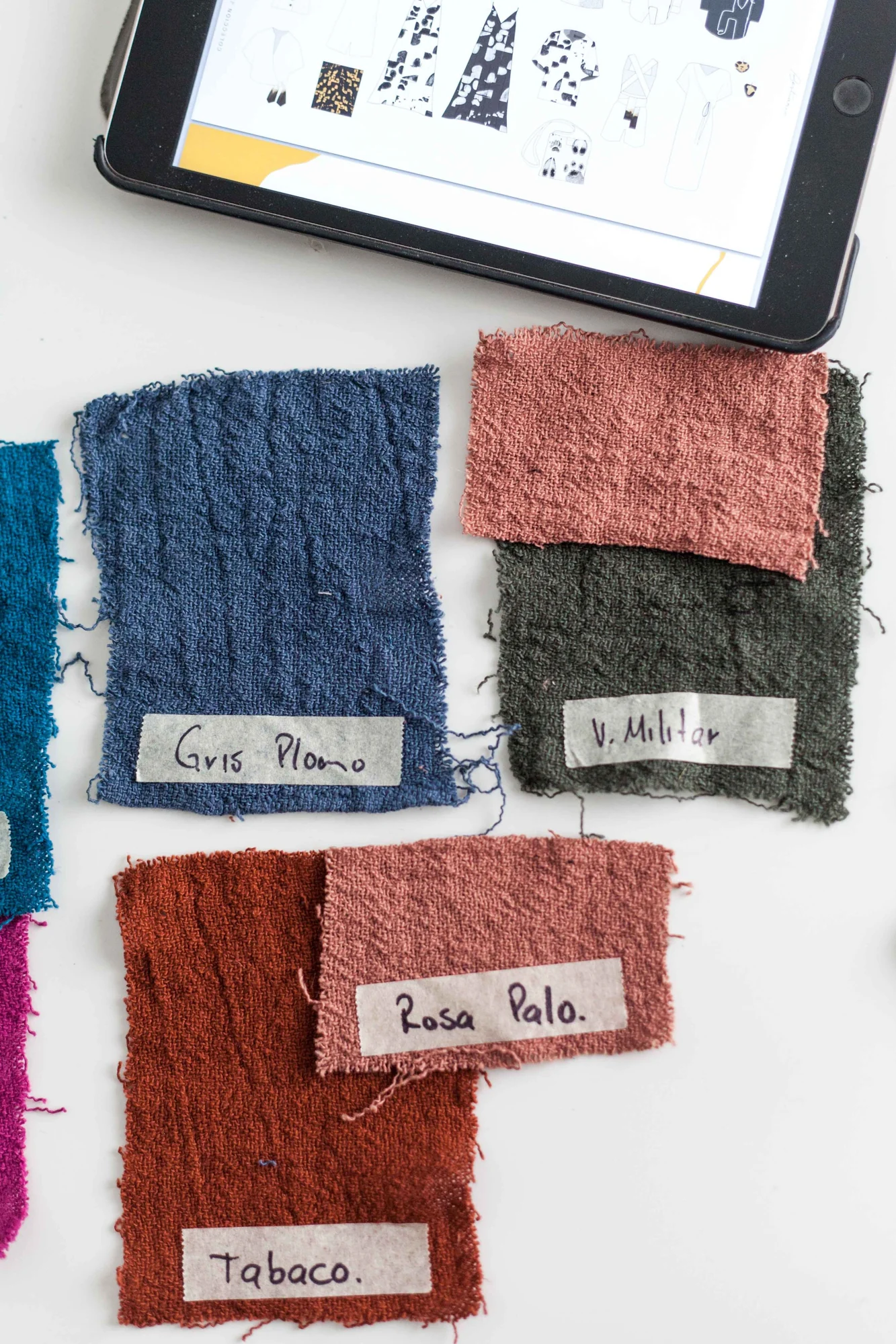 Textured fabric swatches arranged beside a tablet.